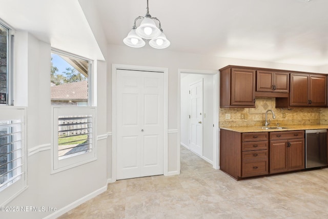 kitchen with baseboards, a sink, decorative backsplash, dishwasher, and decorative light fixtures