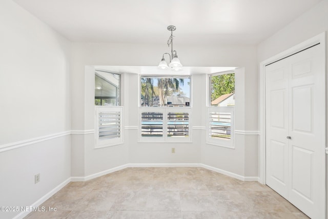 unfurnished dining area with baseboards and an inviting chandelier