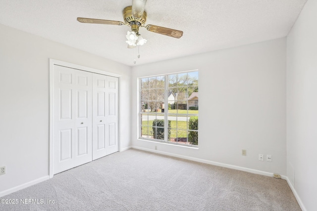 unfurnished bedroom featuring a closet, a textured ceiling, baseboards, and carpet