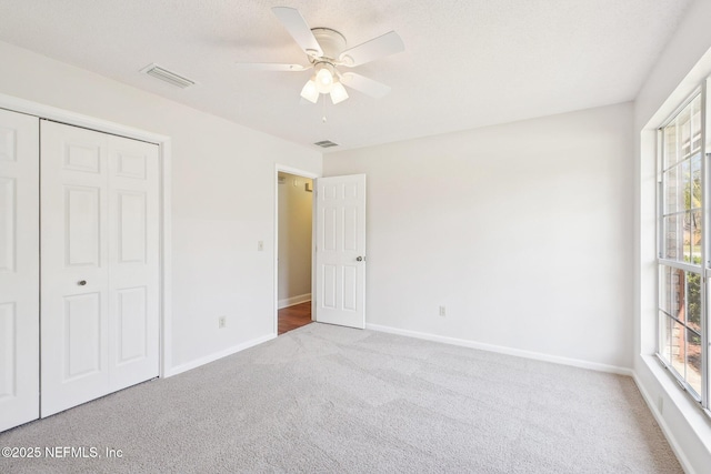 unfurnished bedroom featuring baseboards, visible vents, multiple windows, and carpet floors