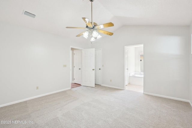 unfurnished bedroom featuring visible vents, lofted ceiling, light colored carpet, and baseboards