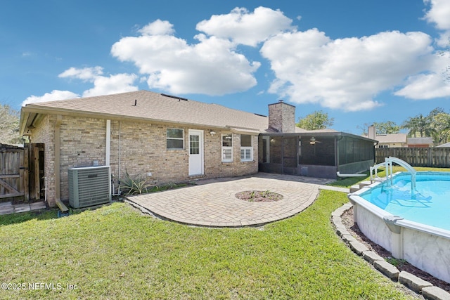 rear view of property featuring a lawn, a patio, central AC, a fenced backyard, and a sunroom