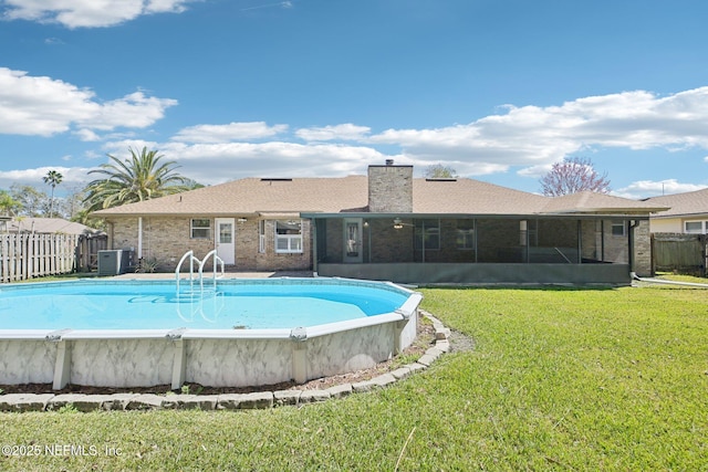 view of pool with a fenced in pool, fence, central AC unit, a yard, and a sunroom