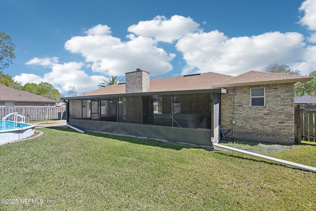 rear view of property featuring a yard, a fenced backyard, brick siding, and a sunroom