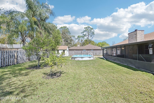 view of yard with a fenced in pool, an outdoor structure, a fenced backyard, and a sunroom