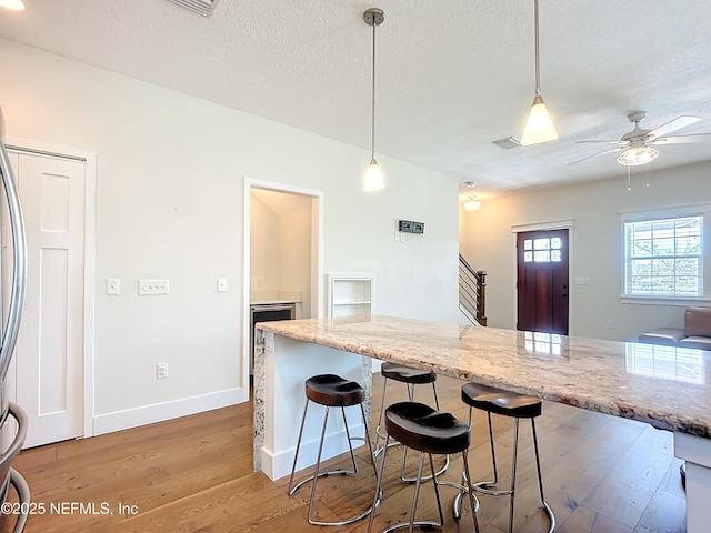 31 Lewis Blvd, Saint Augustine, FL 32084 - kitchen with a breakfast bar, light stone counters, a textured ceiling, wood finished floors, and ceiling fan