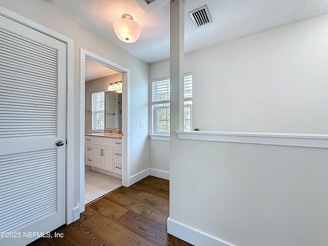 31 Lewis Blvd, Saint Augustine, FL 32084 - hallway featuring visible vents, dark wood-type flooring, a sink, a textured ceiling, and baseboards