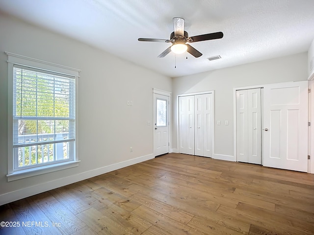 31 Lewis Blvd, Saint Augustine, FL 32084 - unfurnished bedroom with visible vents, two closets, a textured ceiling, wood-type flooring, and baseboards