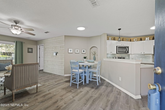 dining room featuring visible vents, a textured ceiling, light wood-type flooring, and ceiling fan