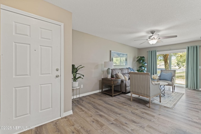 interior space with light wood finished floors, a textured ceiling, baseboards, and ceiling fan