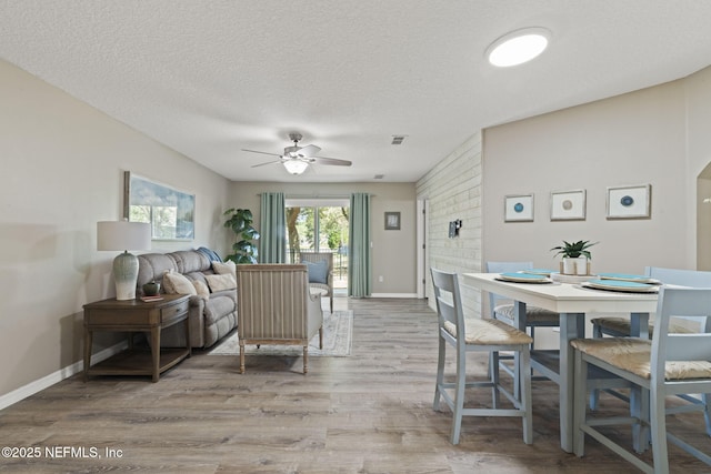 dining room featuring a textured ceiling, wood finished floors, baseboards, and ceiling fan