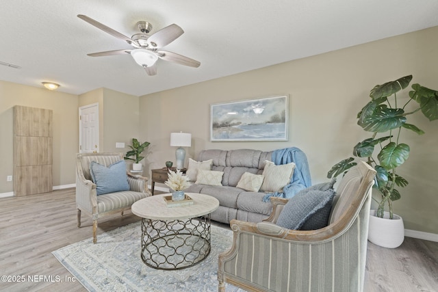 living area featuring visible vents, baseboards, a ceiling fan, and wood finished floors