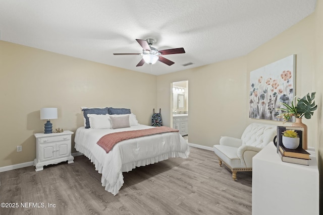 bedroom featuring visible vents, a textured ceiling, baseboards, and wood finished floors