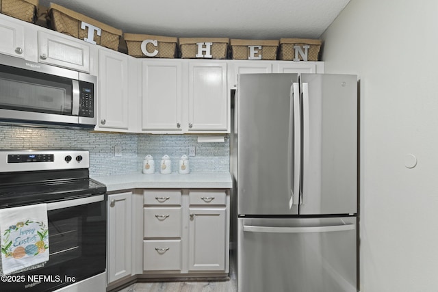 kitchen with light countertops, light wood-type flooring, decorative backsplash, white cabinets, and stainless steel appliances