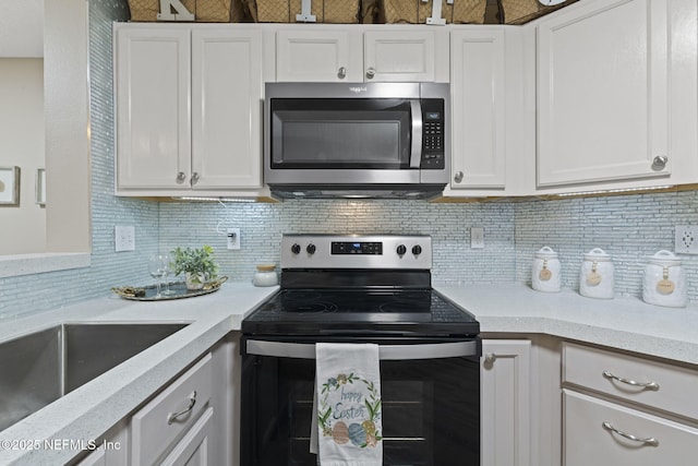 kitchen featuring decorative backsplash, stainless steel microwave, electric range, and white cabinets