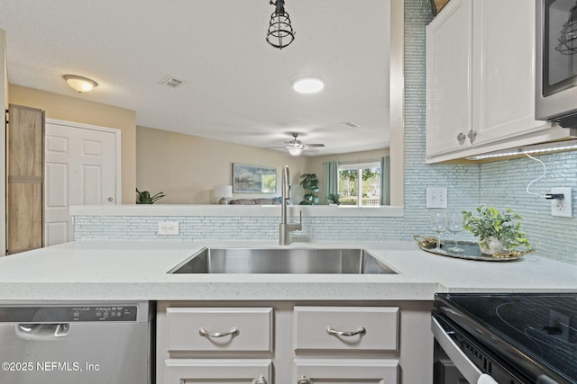 kitchen with visible vents, backsplash, appliances with stainless steel finishes, white cabinets, and a sink