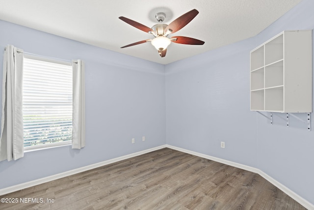 empty room featuring baseboards, wood finished floors, and a ceiling fan