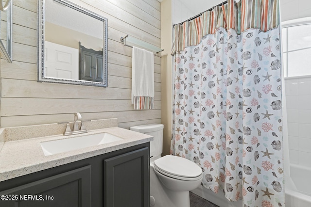 bathroom featuring vanity, toilet, shower / bath combo with shower curtain, and wood walls