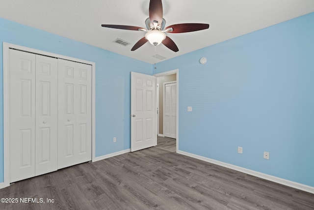 unfurnished bedroom featuring visible vents, a ceiling fan, wood finished floors, a closet, and baseboards