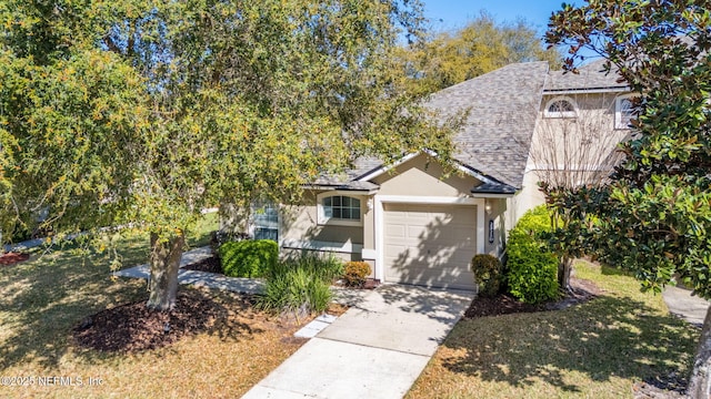 view of front facade with stucco siding, driveway, a front lawn, an attached garage, and a shingled roof