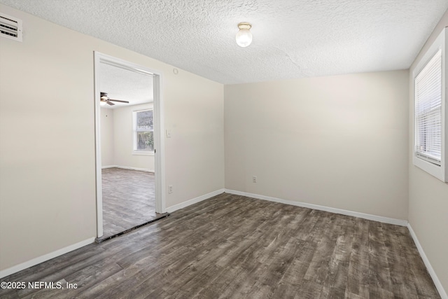 unfurnished room with visible vents, a textured ceiling, baseboards, and wood finished floors