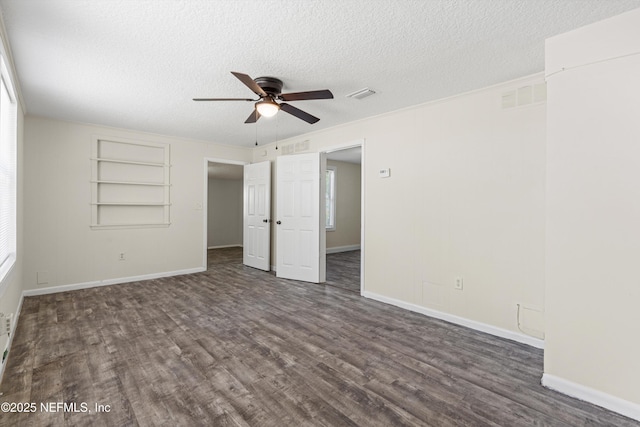 unfurnished bedroom featuring dark wood finished floors, visible vents, a textured ceiling, and baseboards