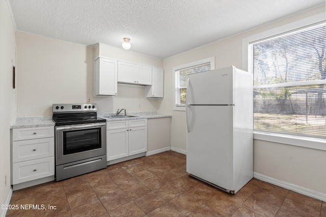 kitchen with electric stove, a sink, white cabinetry, freestanding refrigerator, and light countertops