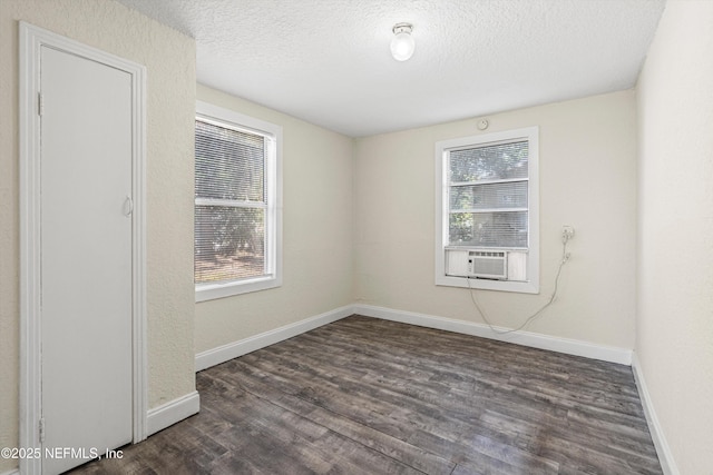 spare room featuring dark wood finished floors, baseboards, and a textured ceiling