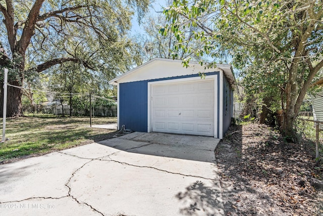 detached garage with concrete driveway and fence