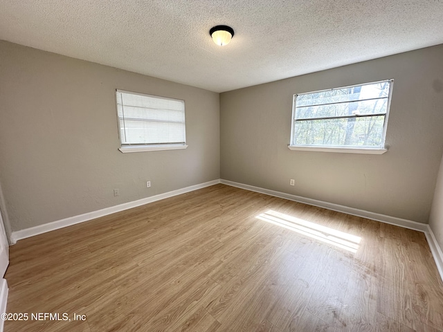 spare room featuring baseboards, a textured ceiling, and wood finished floors