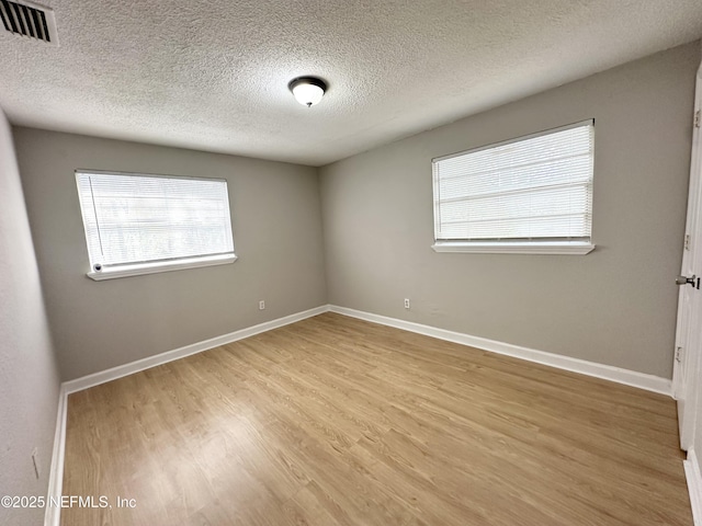 unfurnished room with visible vents, a textured ceiling, baseboards, and light wood-style floors