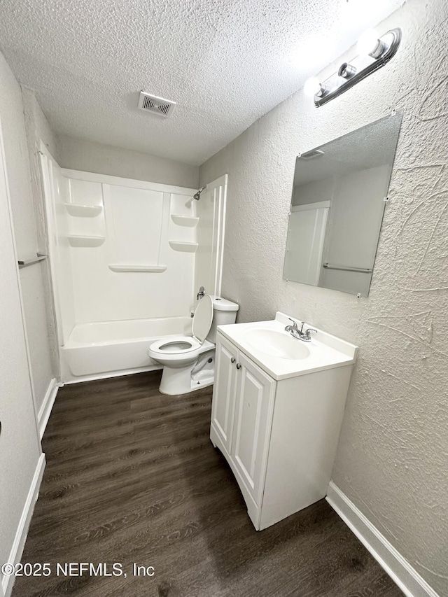 bathroom featuring visible vents, toilet, a textured ceiling, wood finished floors, and a textured wall