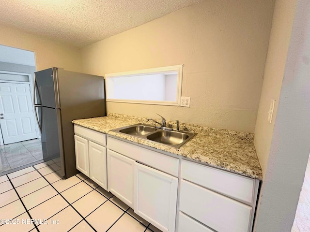 kitchen with white cabinets, a textured ceiling, light countertops, and a sink