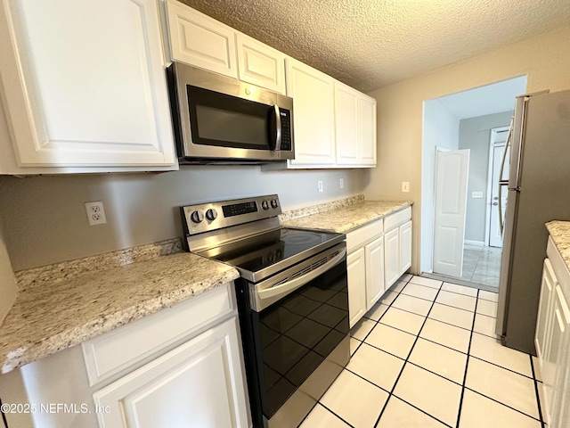 kitchen featuring light countertops, appliances with stainless steel finishes, light tile patterned flooring, a textured ceiling, and white cabinetry