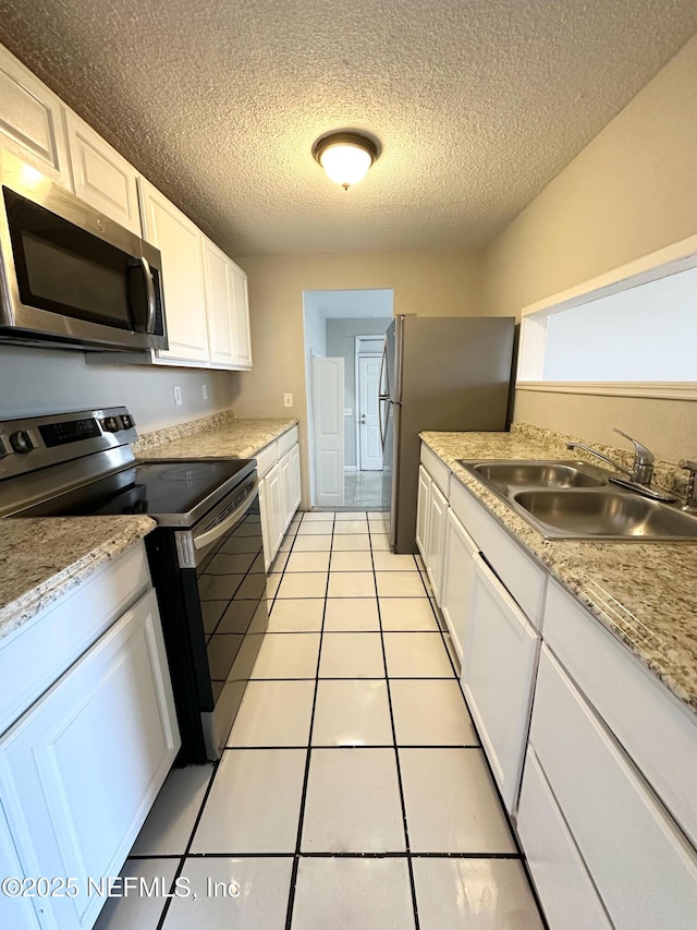 kitchen featuring a sink, appliances with stainless steel finishes, white cabinets, light tile patterned flooring, and light countertops