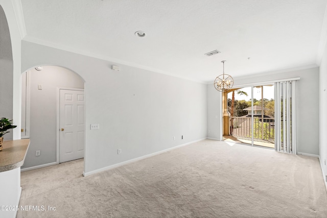 spare room featuring visible vents, arched walkways, ornamental molding, a notable chandelier, and light colored carpet