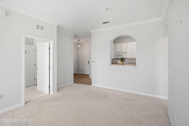 unfurnished room with visible vents, baseboards, light colored carpet, and ornamental molding