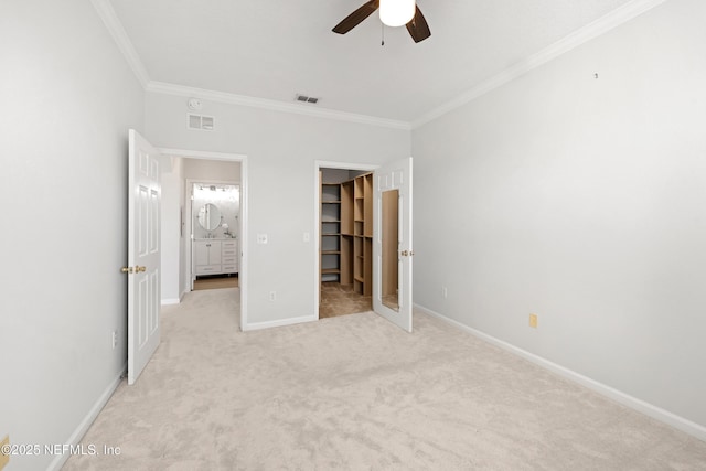 unfurnished bedroom with a walk in closet, baseboards, visible vents, and ornamental molding