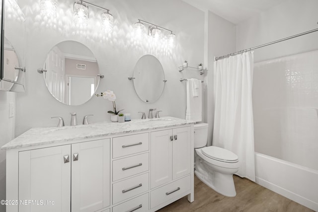 full bath with double vanity, wood finished floors, toilet, and a sink