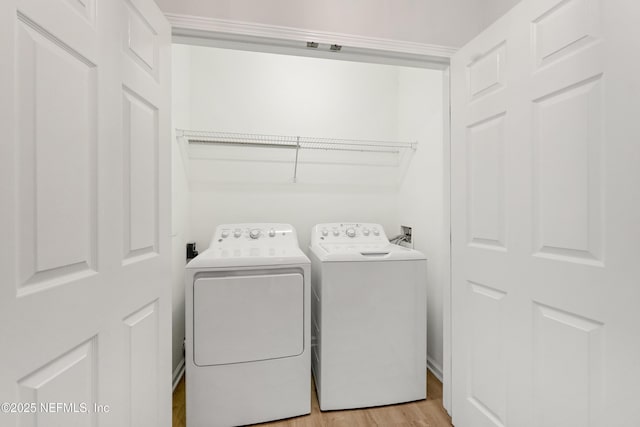 clothes washing area featuring laundry area, washing machine and dryer, and light wood-type flooring