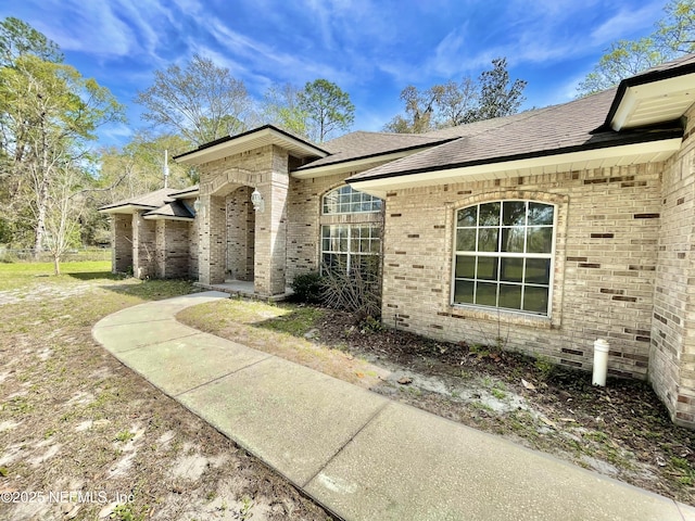 view of front of home with brick siding and roof with shingles