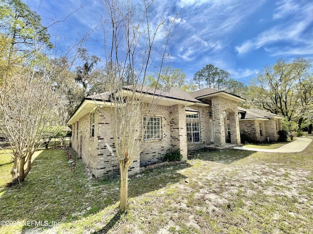 view of home's exterior with a lawn, brick siding, and crawl space