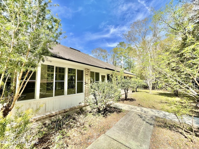 view of side of home featuring a lawn and roof with shingles