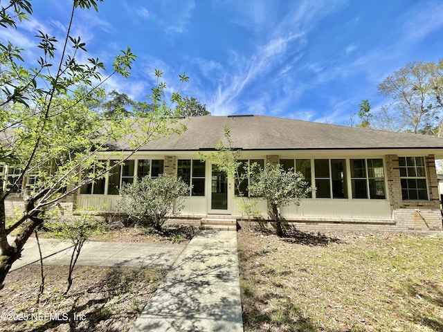 view of front facade featuring a shingled roof and a sunroom