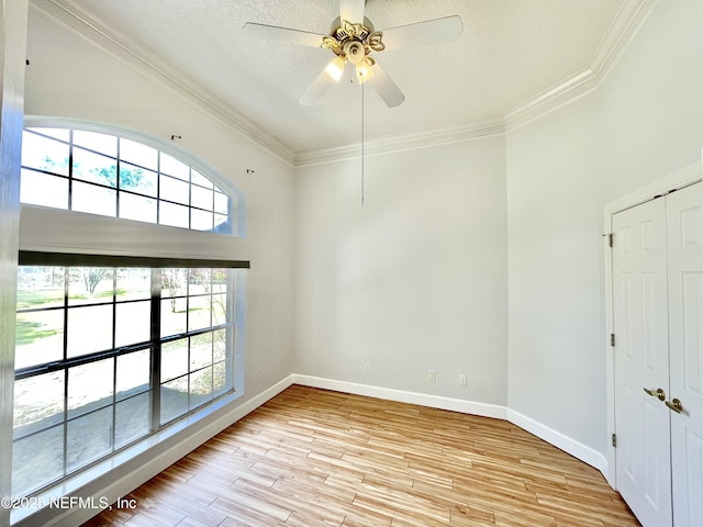 unfurnished room with baseboards, ornamental molding, light wood-style flooring, a textured ceiling, and a ceiling fan