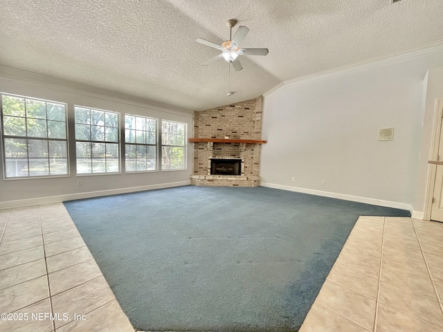 unfurnished living room featuring a ceiling fan, a fireplace, tile patterned flooring, crown molding, and lofted ceiling