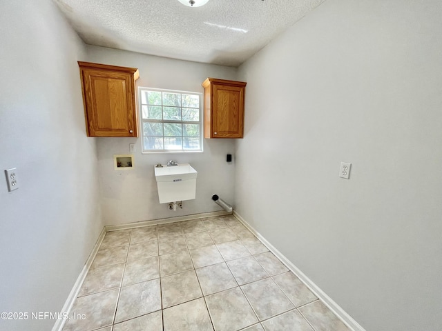 clothes washing area with baseboards, cabinet space, a sink, washer hookup, and a textured ceiling