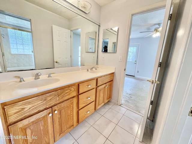 full bath with tile patterned flooring, plenty of natural light, a ceiling fan, and a sink