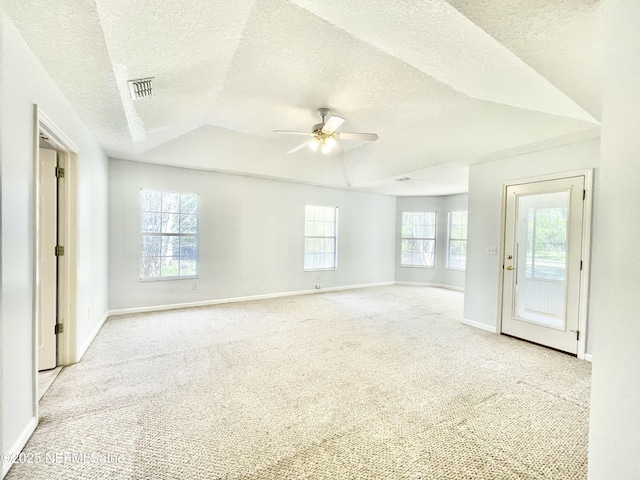 carpeted spare room featuring visible vents, a healthy amount of sunlight, baseboards, and a ceiling fan