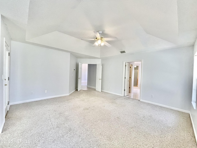 unfurnished bedroom with visible vents, a textured ceiling, baseboards, a raised ceiling, and light colored carpet